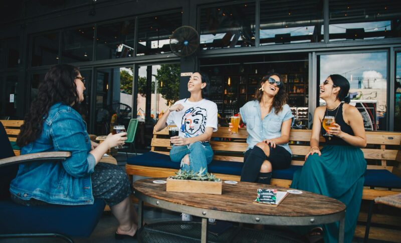 four women chatting while sitting on bench