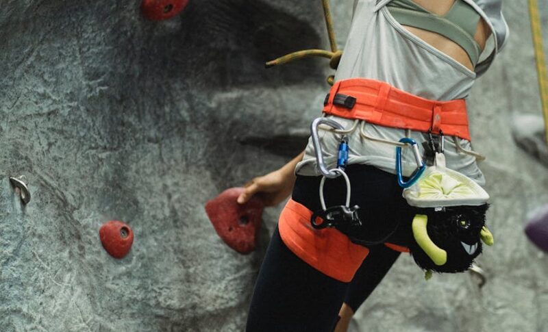 anonymous fit female alpinist practicing bouldering in climbing gym